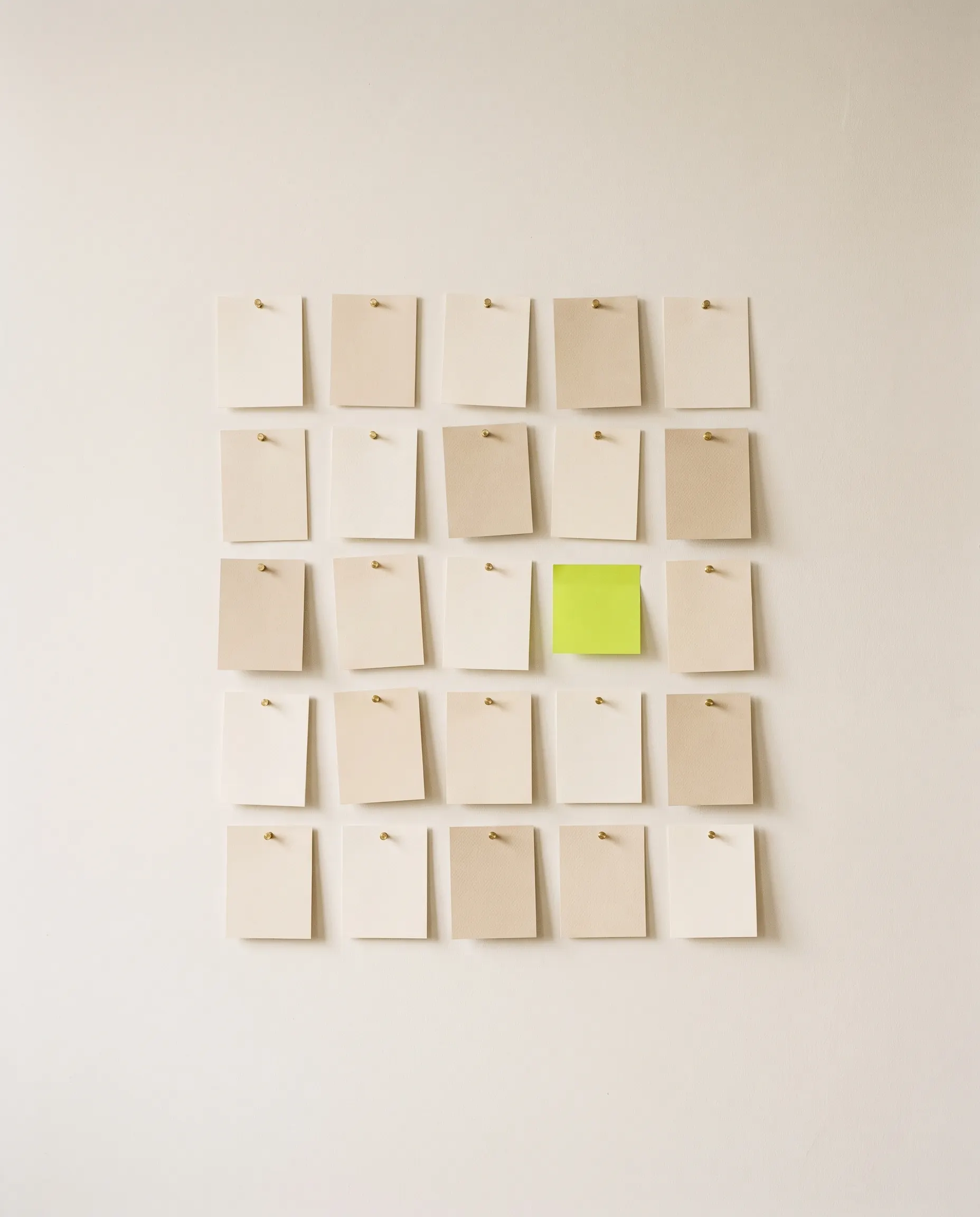 A wall of small blank cards, one of them acid green